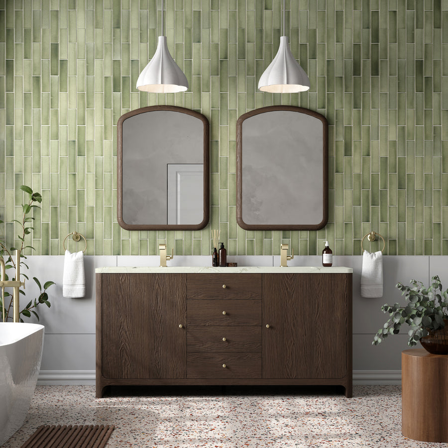 Modern bathroom with green vertical tile walls, two arched mirrors above a Gracyn 72" Vanity, gold faucets, pendant lights, white towels, a potted plant, and terrazzo flooring.