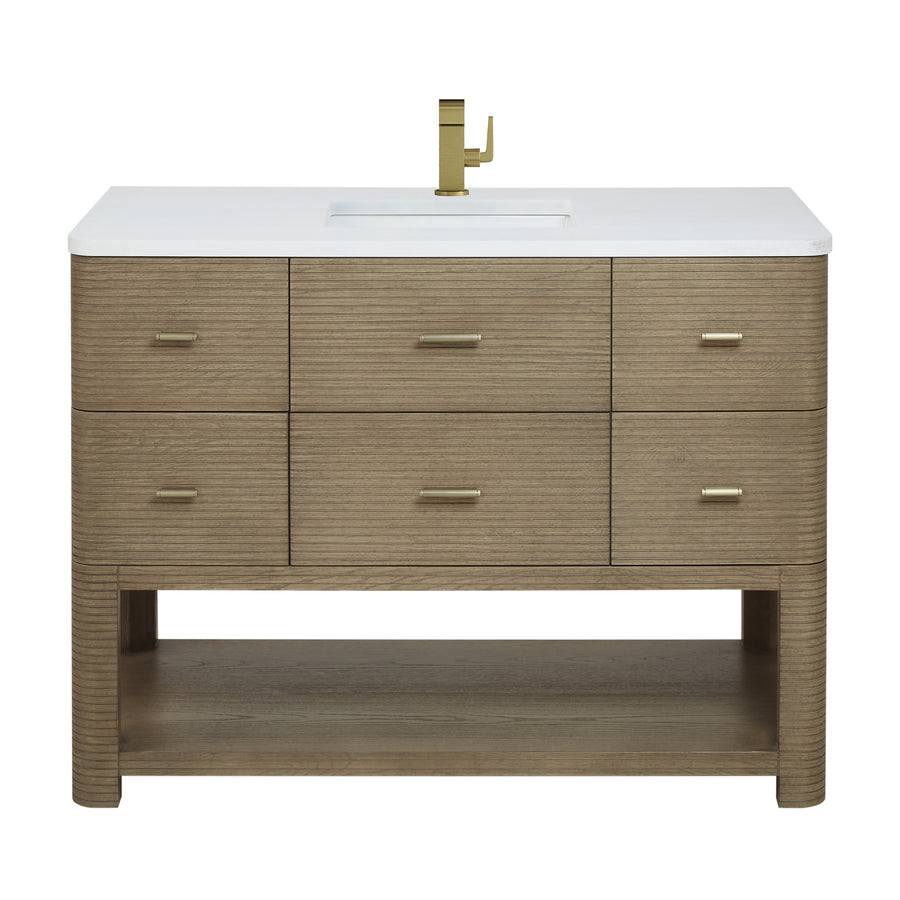 A modern wooden bathroom vanity with six drawers, gold handles, a white countertop, an integrated rectangular sink, a gold faucet, and an open shelf at the bottom.
