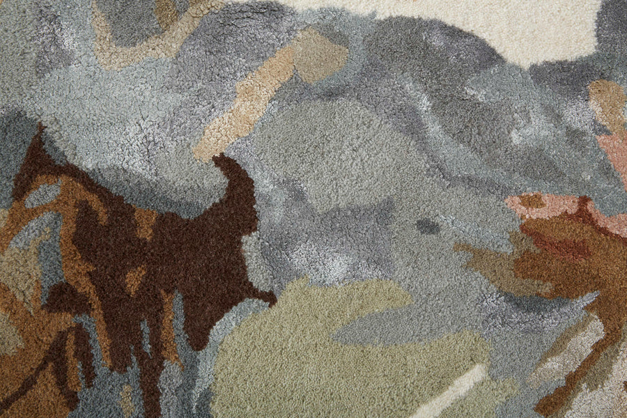 Close-up of a textured, abstract rug in muted tones of gray, brown, green, and beige, with irregular shapes blending into each other.