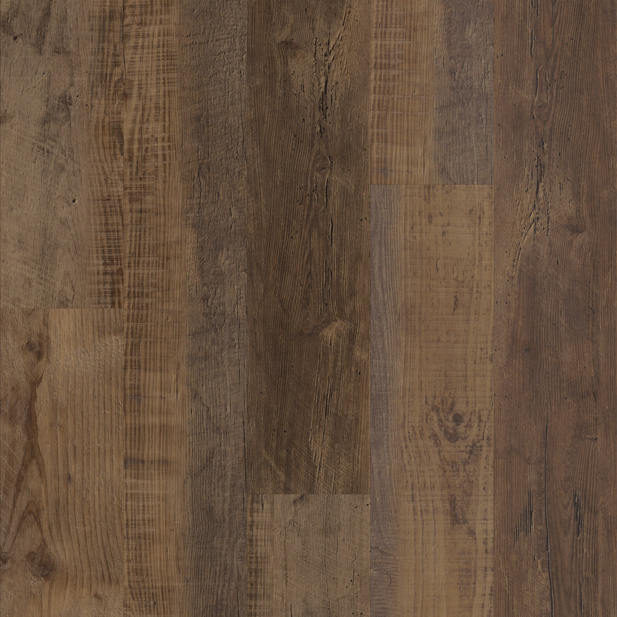 Close-up view of a Coretec Pro Plus Vinyl floor with wide planks in varied brown tones, showcasing visible grain patterns, knots, and textured surfaces for an authentic luxury flooring appearance.