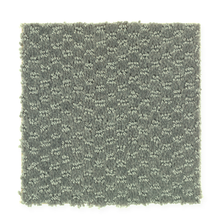 A square swatch of Dynamo Family Friendly Carpet in Turf, featuring gray textured fabric with a subtle geometric pattern, is displayed on a white background.