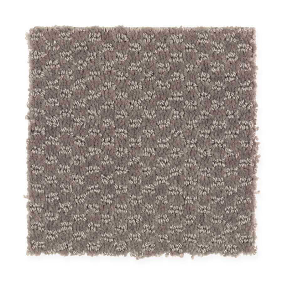 A square swatch of Dynamo Family Friendly Carpet in Roosevelt, featuring a textured, looped pattern with mixed light and dark threads for a subtle geometric look. Edges are unfinished.