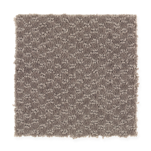 A square swatch of Dynamo Family Friendly Carpet in Roosevelt, featuring a textured, looped pattern with mixed light and dark threads for a subtle geometric look. Edges are unfinished.