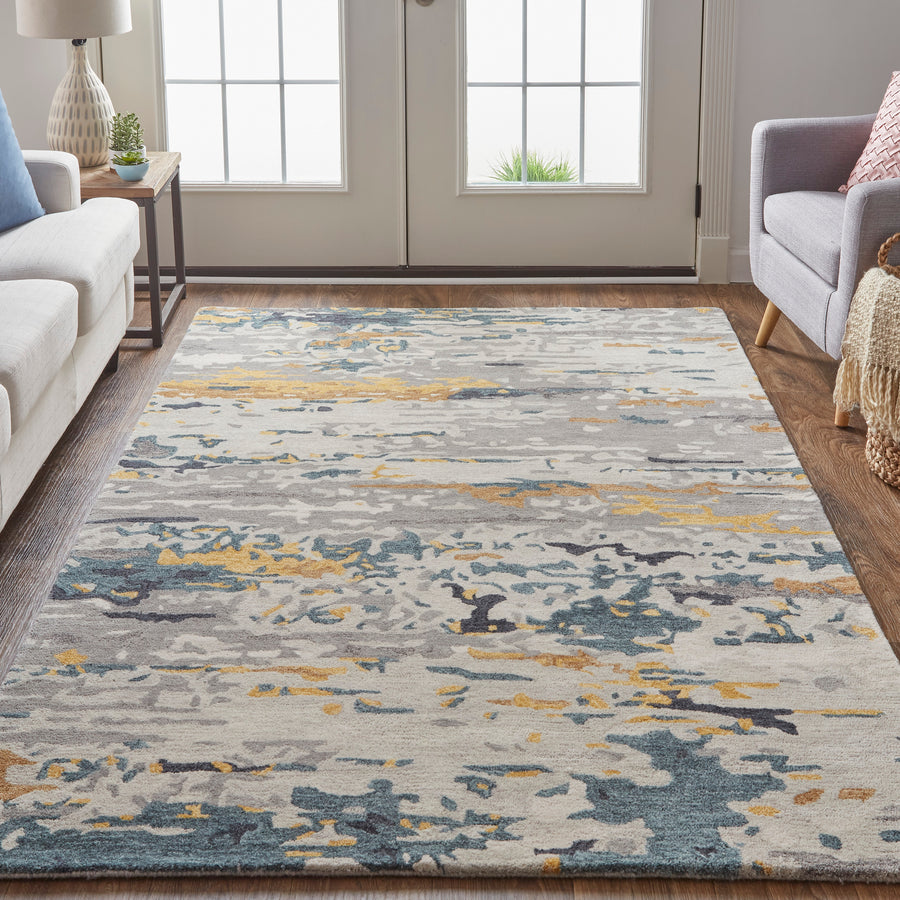 A modern living room showcases the Everley Gray Area Rug, boasting an elegant design in blue, gray, yellow, and white on a wooden floor around light sofas and natural light—ideal for elevated home décor.