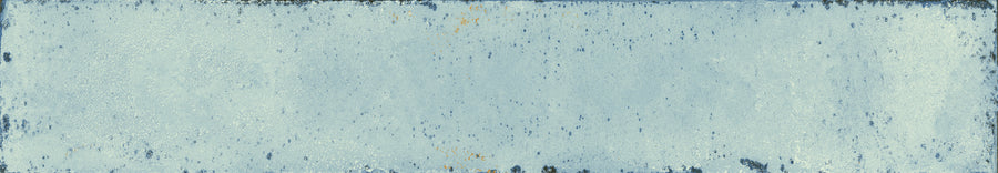 The Eclipse 2x18 Glazed Porcelain Tile features a rectangular shape, weathered blue finish, rough texture, faded paint, rust spots, and chipped edges for a distressed vintage look—ideal as an architectural tile for distinctive spaces.