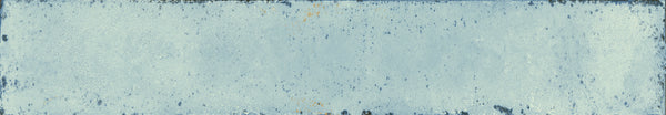 The Eclipse 2x18 Glazed Porcelain Tile features a rectangular shape, weathered blue finish, rough texture, faded paint, rust spots, and chipped edges for a distressed vintage look—ideal as an architectural tile for distinctive spaces.