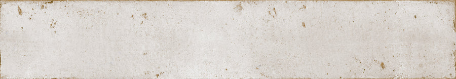 Featuring a rectangular, textured surface with distressed details, Eclipse 2x18 Glazed Porcelain Tile has an off-white finish with brown stains, scratches, and worn edges that evoke vintage architectural tile.