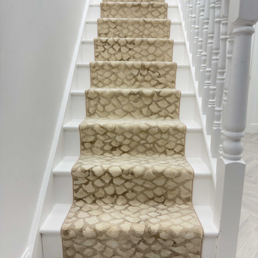 A white staircase features the Eclipse 64194-8565 Runner Rug in beige and cream, paired with white balusters, a right-side handrail, and crisp white walls for a clean, bright entryway look.