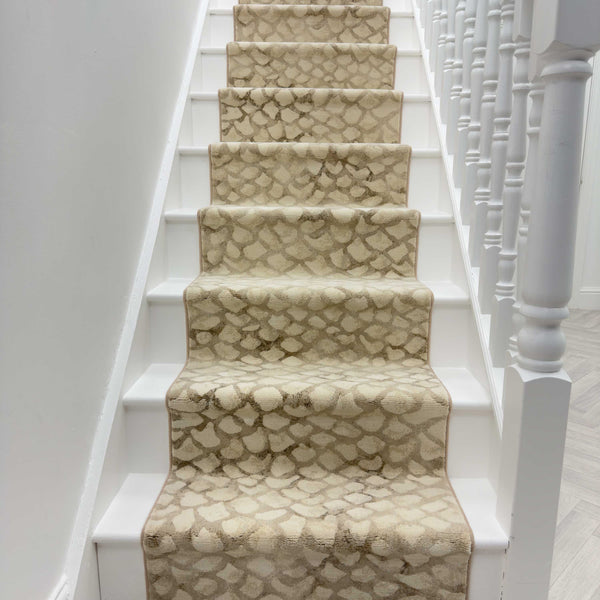 A white staircase features the Eclipse 64194-8565 Runner Rug in beige and cream, paired with white balusters, a right-side handrail, and crisp white walls for a clean, bright entryway look.