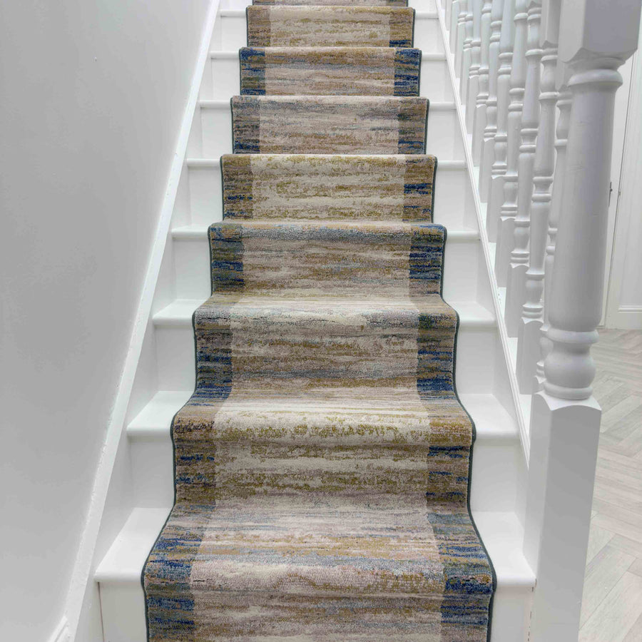 The Eclipse 79138-7696 Runner Rug in beige, brown, and blue adds a soft, textured touch to white stairs and railings—ideal for enhancing any hallway rug style.