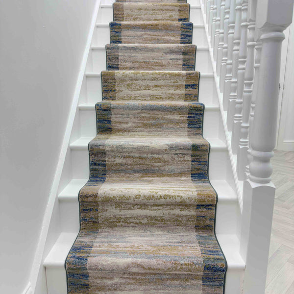 The Eclipse 79138-7696 Runner Rug in beige, brown, and blue adds a soft, textured touch to white stairs and railings—ideal for enhancing any hallway rug style.