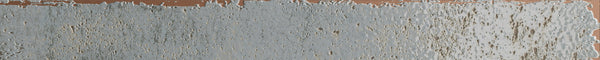 A close-up of the Emerge 2x20 Porcelain Tile in Aurora color, showcasing its textured surface with light blue-gray tones and brownish undertones for an uneven, weathered look.