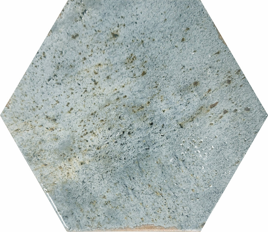 The Emerge 8x9 Hexagon Porcelain Tile in Aurora features a speckled gray and blue pattern with natural-looking stone variation, showcasing varying shades and small dark spots across its surface.