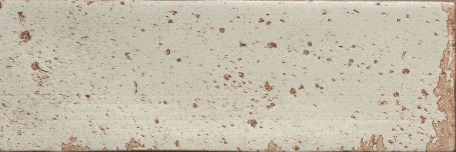 The Emerge 3x8 Porcelain Tile in First Light features a light beige base with irregular brown speckles, softly worn edges revealing more brown, and a subtle surface texture that enhances its natural look.