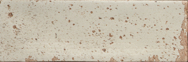 The Emerge 3x8 Porcelain Tile in First Light features a light beige base with irregular brown speckles, softly worn edges revealing more brown, and a subtle surface texture that enhances its natural look.