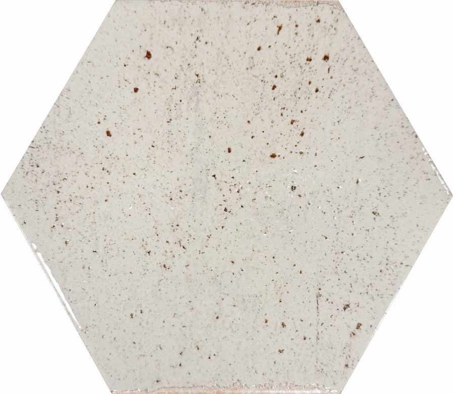 The Emerge 8x9 Hexagon Porcelain Tile in First Light features a white, slightly glossy finish with small brown speckles and natural variation, adding relaxed beauty to any space.