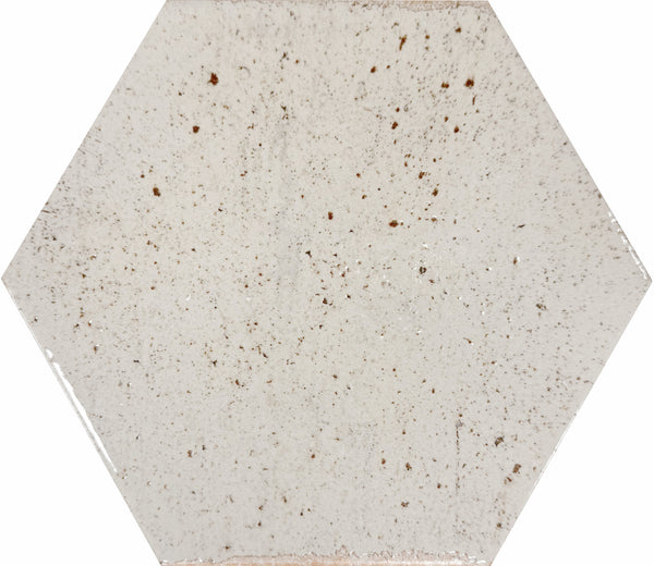 The Emerge 8x9 Hexagon Porcelain Tile in First Light features a white, slightly glossy finish with small brown speckles and natural variation, adding relaxed beauty to any space.