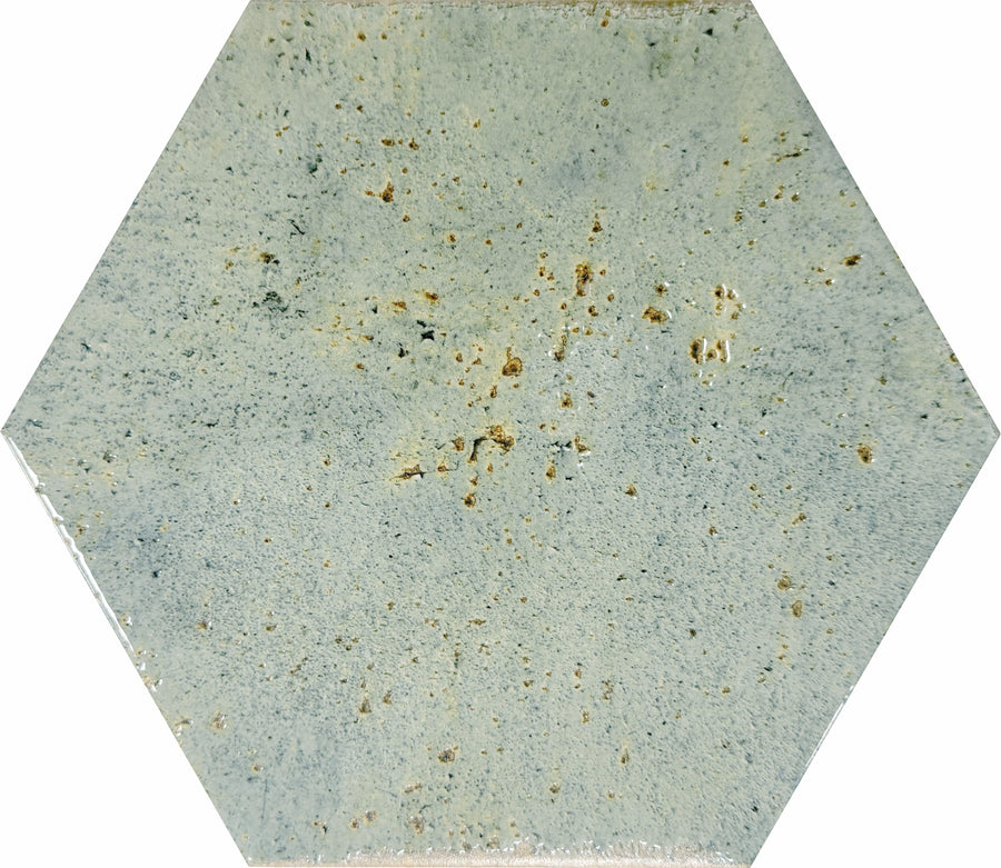 Emerge 8x9 Hexagon Porcelain Tile in Sprout features a light blue-gray shade with subtle speckles and scattered brownish spots, offering natural variation for a textured, slightly rustic look.