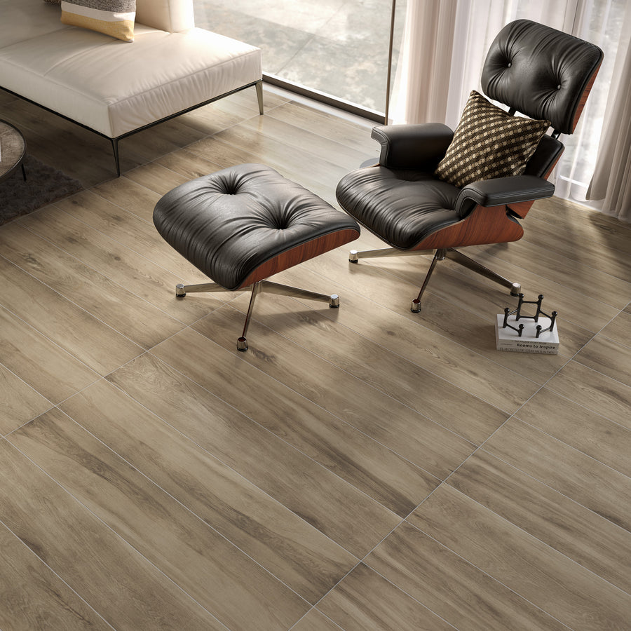 A modern living room with light wood-look tile flooring, a black leather lounge chair with matching ottoman, a white sofa, and sunlight streaming through sheer curtains. A chess set is on the floor next to the chair.