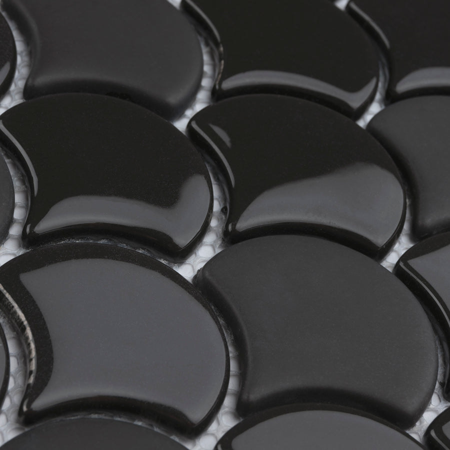 Close-up of glossy, black, crescent-shaped tiles arranged in a repeating pattern with visible white grout lines in between.