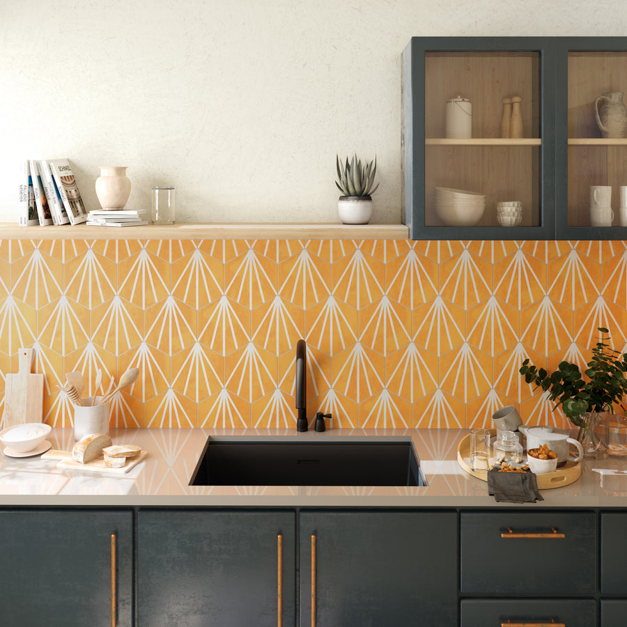 Modern kitchen with a yellow geometric tile backsplash, black sink, dark cabinets with gold handles, glass-front cabinet, open shelves, and various kitchen items on the counter, including dishes, plants, and bread.