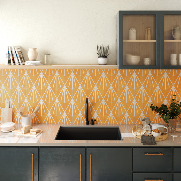 Modern kitchen with a yellow geometric tile backsplash, black sink, dark cabinets with gold handles, glass-front cabinet, open shelves, and various kitchen items on the counter, including dishes, plants, and bread.