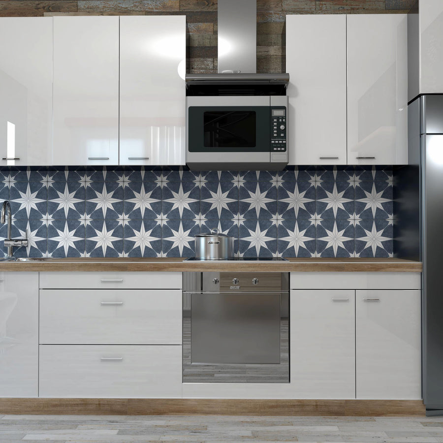 Modern kitchen with glossy white cabinets, stainless steel appliances, a wood countertop, and a stove. The backsplash features a bold dark blue and white geometric star pattern. A silver microwave is mounted above the stove.