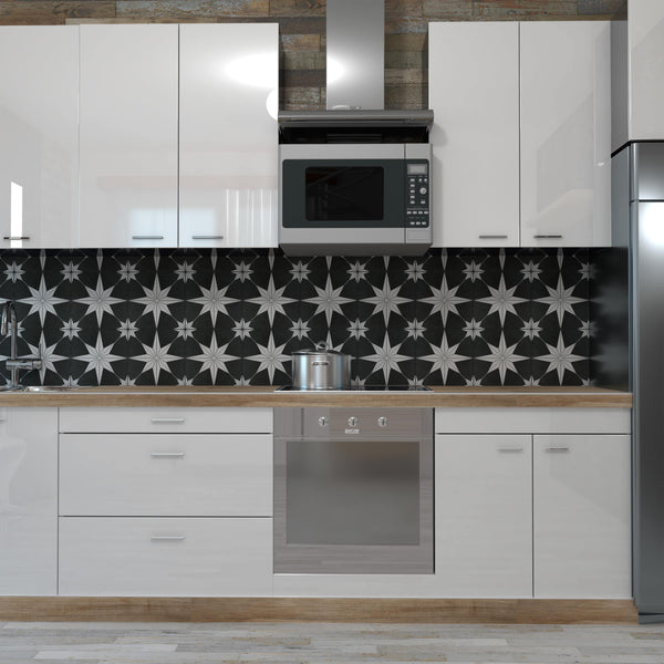Modern kitchen with white cabinets, a black and white geometric tile backsplash, a stainless steel oven, a pot on the stove, a microwave above, and a silver refrigerator on the right.