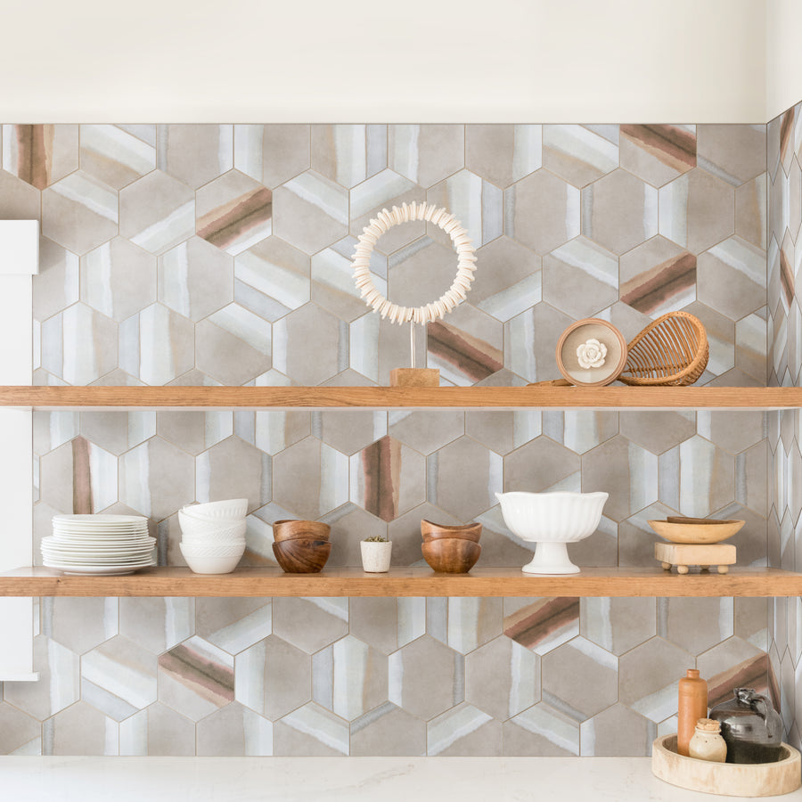 Open wooden shelves against a geometric hexagon-patterned backsplash, displaying dishes, bowls, a plant, wooden decor, ceramics, and kitchen items in neutral and earthy tones.