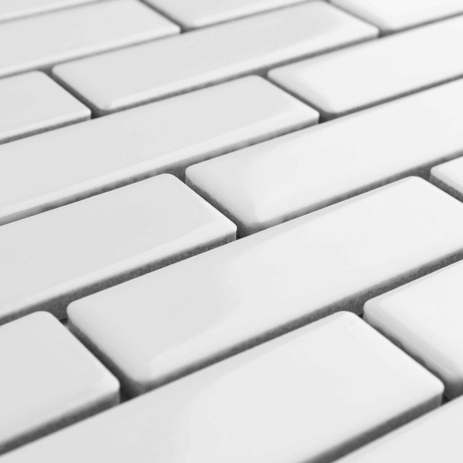 Close-up view of clean, glossy white rectangular tiles arranged in a staggered brick-like pattern with visible grout lines.