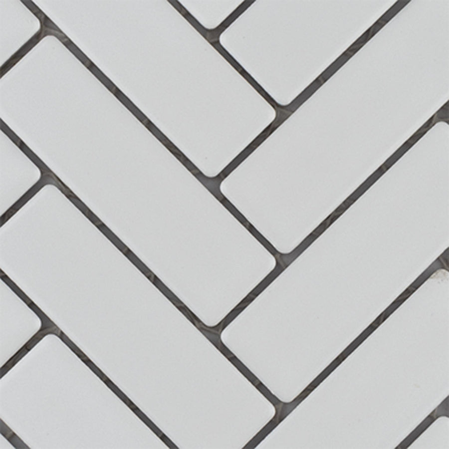 White rectangular tiles arranged in a herringbone pattern with dark grout lines in between, creating a modern and clean geometric design.