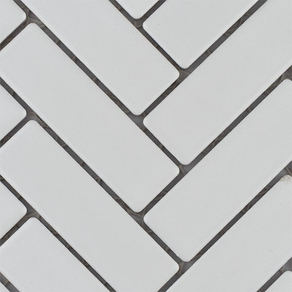 White rectangular tiles arranged in a herringbone pattern with dark grout lines in between, creating a modern and clean geometric design.