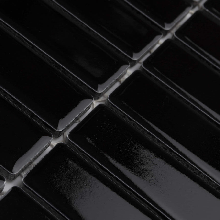 Close-up of glossy black rectangular tiles arranged in a grid pattern with visible grout lines between them.