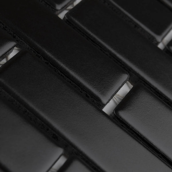 Close-up of a black rectangular tile mosaic with a glossy finish, arranged in a staggered brick pattern. The grout lines between the tiles are visible, highlighting the geometric design.