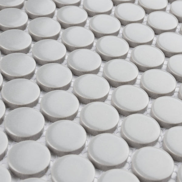 Close-up view of a surface with a repeating pattern of round, light gray tiles arranged in a grid on a white background.