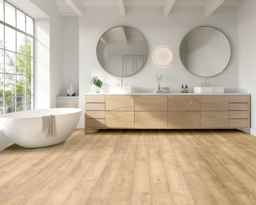 Modern bathroom with a freestanding white bathtub by large windows, light wood double vanity with two sinks and round mirrors, and light wood flooring; bright and airy with minimalist decor.