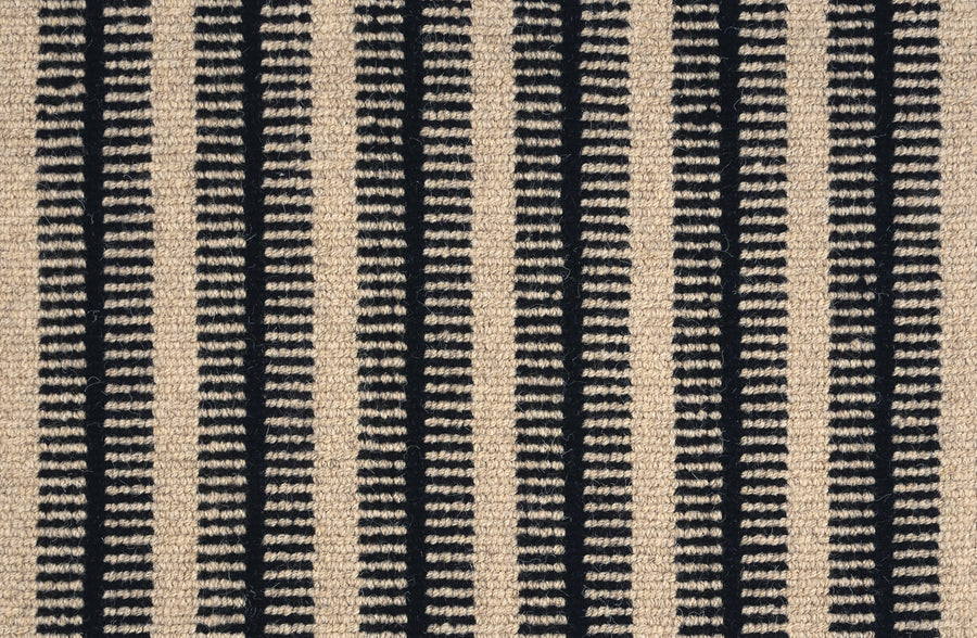 Close-up of the Feng Shui On Trend Carpet, showcasing vertical cream and black stripes with a textured, slightly raised look. Black stripes have small cream dashes, making it ideal for luxurious home decor or any stylish carpet collection.