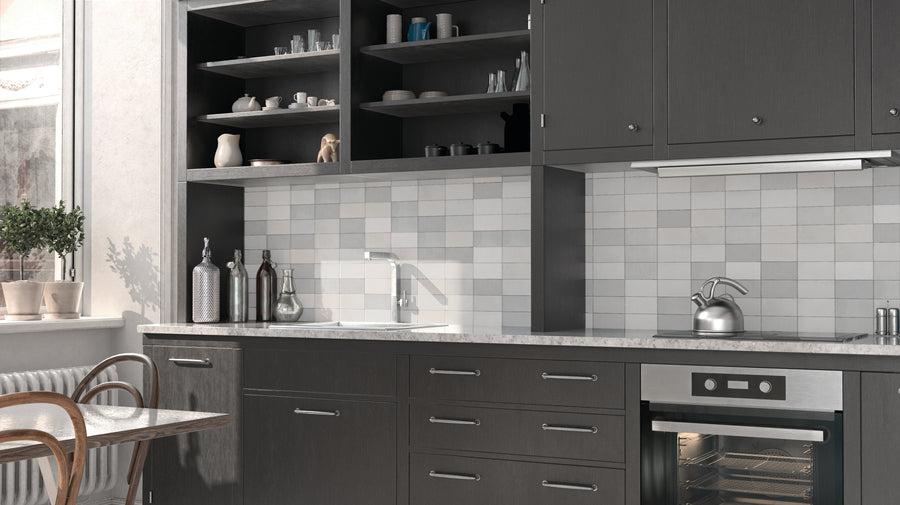 Modern kitchen with dark cabinets, open shelving displaying dishes, a marble countertop, a built-in oven, a kettle on the stove, a white tile backsplash, and a window with potted plants and wooden chairs.