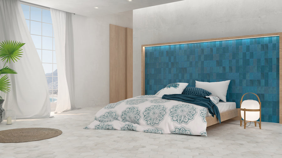 Modern bedroom with a large teal headboard, bed with white and teal patterned bedding, round bedside lamp, large window with white curtains, a potted plant, and minimalist decor. Bright natural light fills the room.