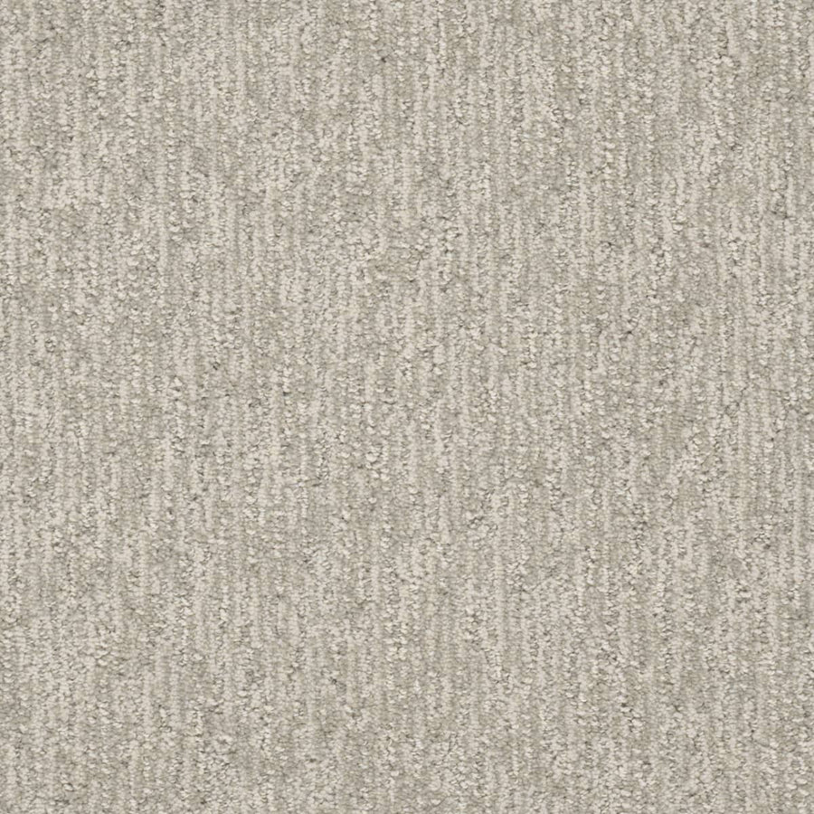 A close-up of Finishing Touch Berber Carpet in Heirloom shows a textured, light gray surface with a subtle vertical linear pattern, offering soft yet durable comfort and slight shading variations—ideal for high-traffic areas.