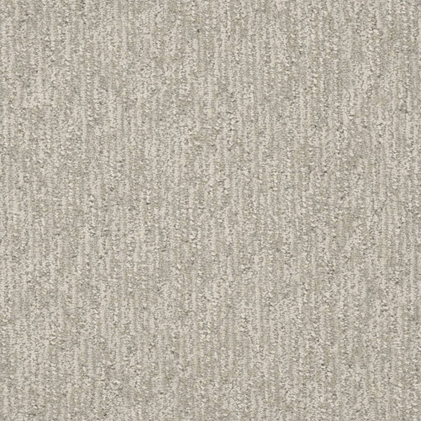 A close-up of Finishing Touch Berber Carpet in Heirloom shows a textured, light gray surface with a subtle vertical linear pattern, offering soft yet durable comfort and slight shading variations—ideal for high-traffic areas.