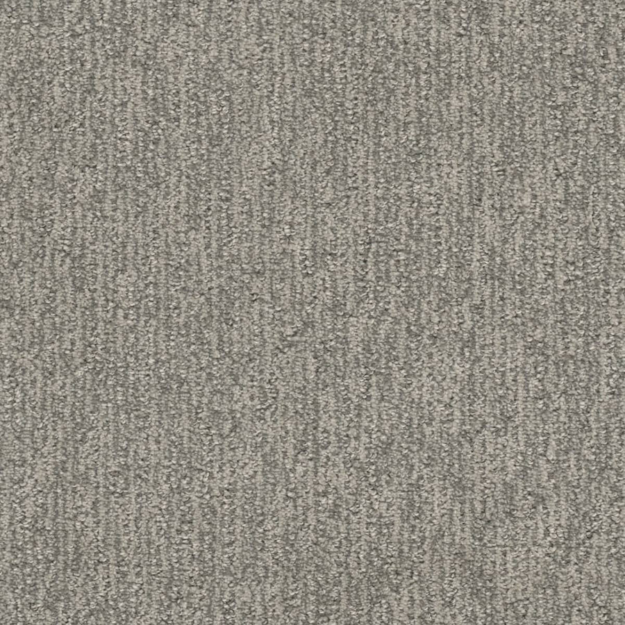 A close-up view of Finishing Touch Berber Carpet in Seaside—a durable option for high-traffic areas, featuring a textured surface with subtle linear patterns and a blend of light and dark gray fibers.