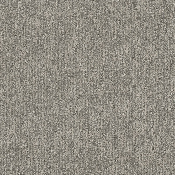 A close-up view of Finishing Touch Berber Carpet in Seaside—a durable option for high-traffic areas, featuring a textured surface with subtle linear patterns and a blend of light and dark gray fibers.