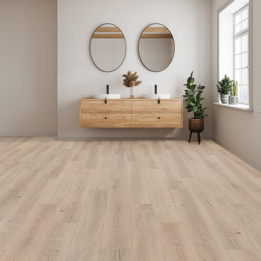 A minimalist bathroom with Woodlette Estates 7 1/2" Waterproof Laminate flooring in a natural wood look, floating double vanity, round mirrors, potted plants, and a large window for natural light. The space feels clean, airy, and modern.