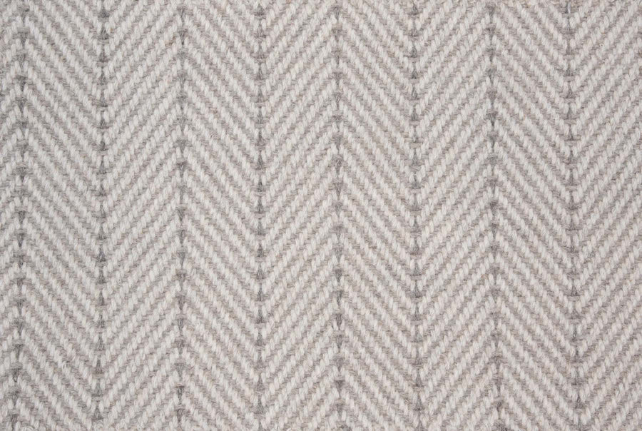 Close-up of Angola Berber Carpet in Fossil color, featuring a repeating chevron pattern that resembles herringbone—an ideal, durable flooring choice for contemporary style interiors.