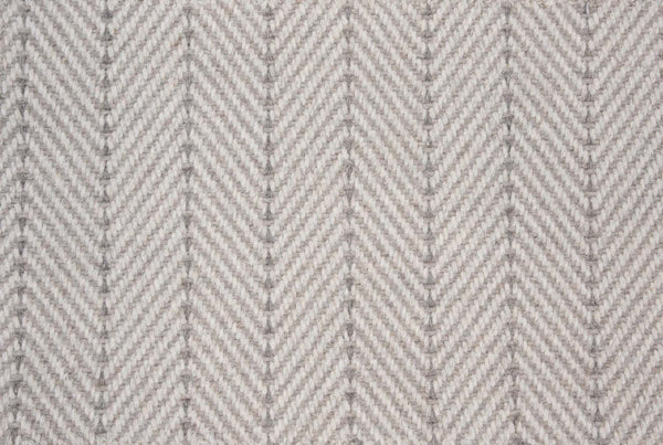 Close-up of Angola Berber Carpet in Fossil color, featuring a repeating chevron pattern that resembles herringbone—an ideal, durable flooring choice for contemporary style interiors.