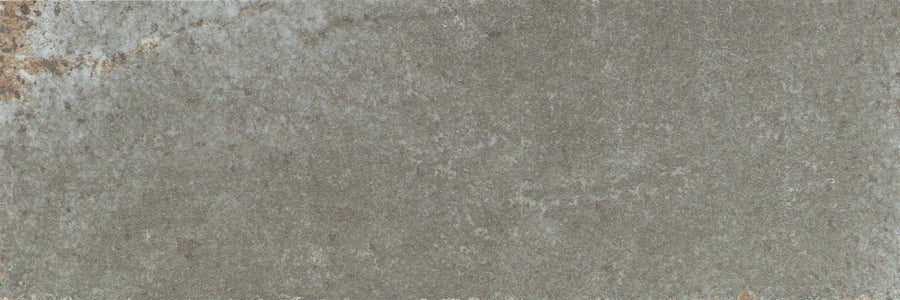 A close-up of the Catalyst 4x12 Porcelain Tile in Fuse Grey, showcasing its textured stone surface with subtle brown and white accents and natural slate-like patterns.