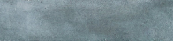 The Galaxy 2x10 Porcelain Tile features a textured blue-gray surface with subtle color variations, reminiscent of painted concrete—ideal for luxury tiling projects or as a sophisticated glazed porcelain accent.