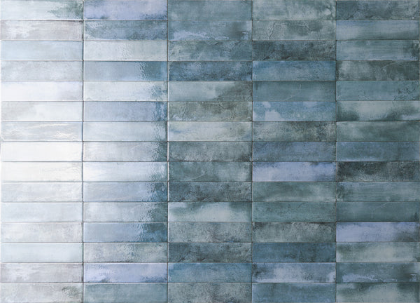 A wall covered with rectangular, glossy blue and gray tiles arranged in a horizontal grid pattern, creating a textured and slightly reflective surface.