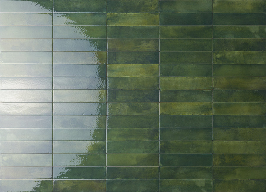 Rectangular green ceramic tiles arranged in a grid pattern on a wall, with the left side showing a glossy, reflective surface and the right side appearing matte.